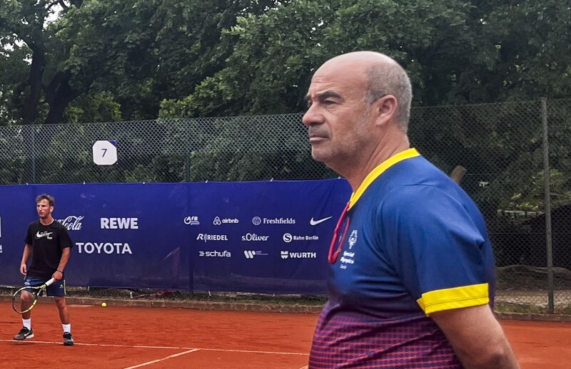 Das Bild zeigt den spanischen Trainer Juan, wie er auf dem Sandplatz aufmerksam das Abschlusstraining seiner Schützlinge verfolgt.