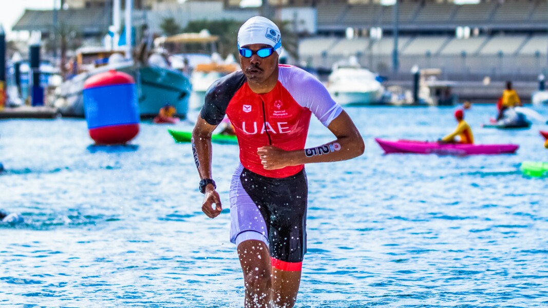Das Foto zeigt einen Triathleten, der gerade aus dem Wasser steigt. Er pustet kräftig durch.