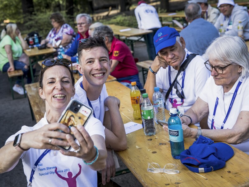 The photo shows a scene during the family reception of the National Games. Four people are sitting together at a table and a woman is taking a selfie of them all.