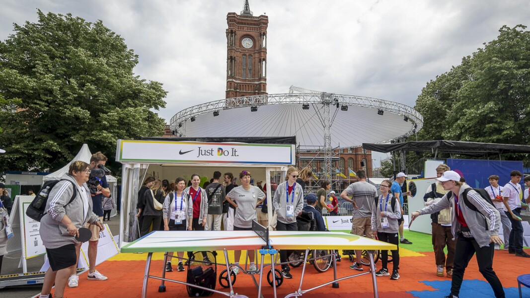 The photo shows visitors of the SO festival. Some are playing table tennis, others are watching. The mood is relaxed.