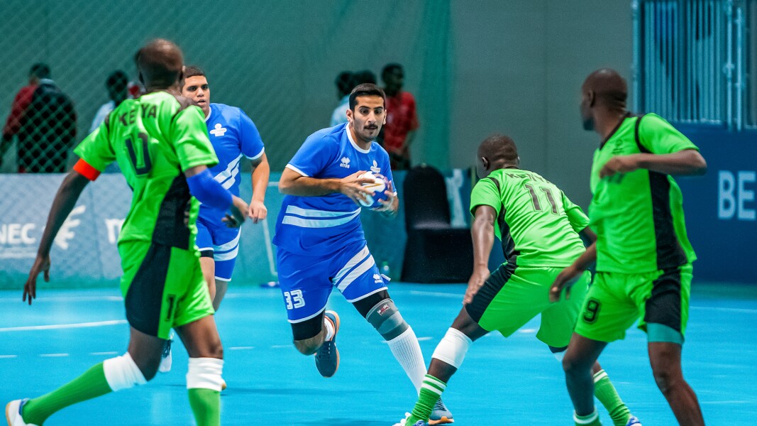 Das Foto zeigt eine Spielszene beim Handball. Ein Spieler ist dynamische mit Ball unterwegs und die andere Mannschaft versucht ihn zu verteidigen.