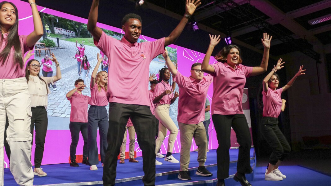 The photo shows participants of the GYLS. They are dancing on the stage, raising their arms and laughing.